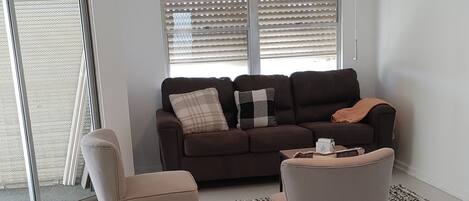 A living room with a ceiling fan, a sofa, two armchairs, and a patterned rug.