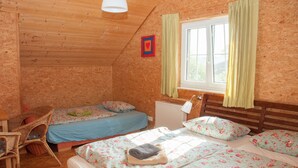 Ein gemütliches Zimmer mit zwei Betten, einem Sessel und einem Fenster mit Vorhängen.