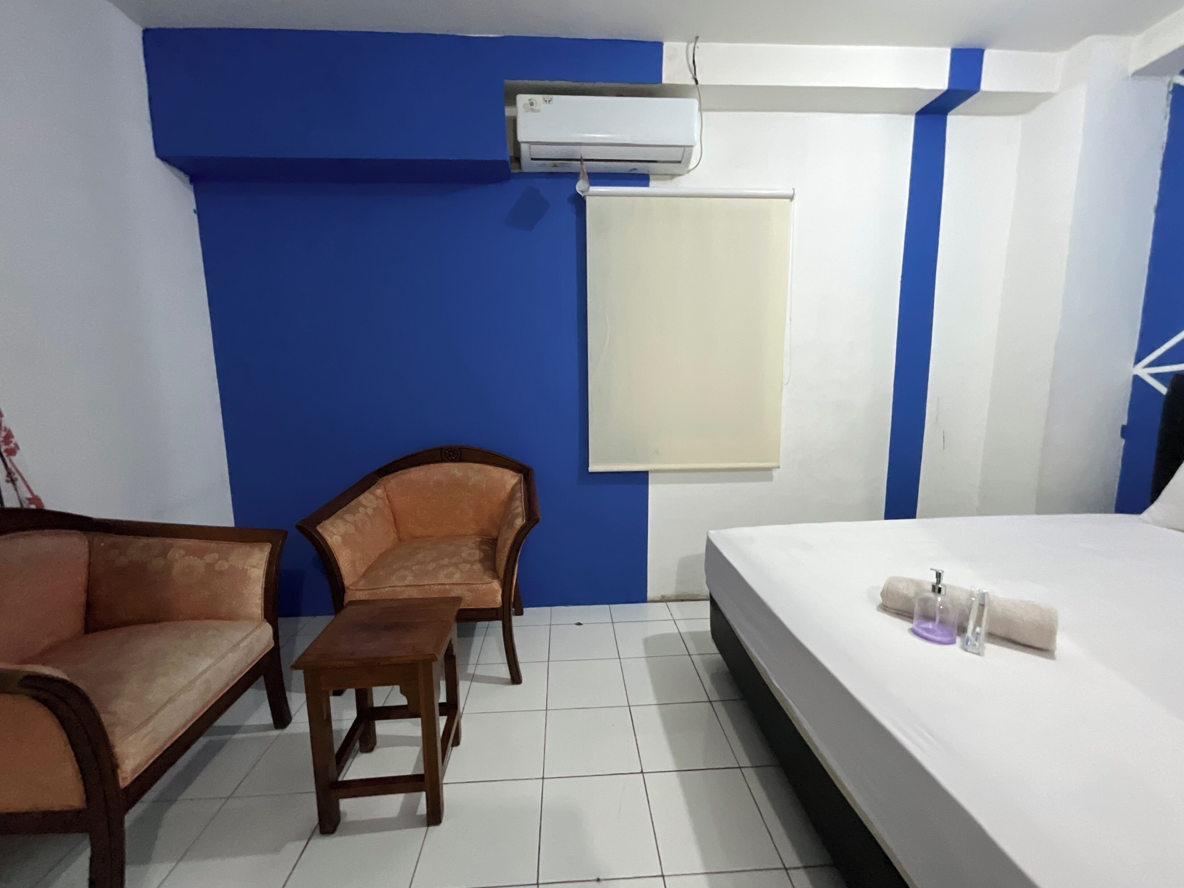 Quarto de hotel com cama, dois sofás, uma mesinha e ar condicionado na parede.