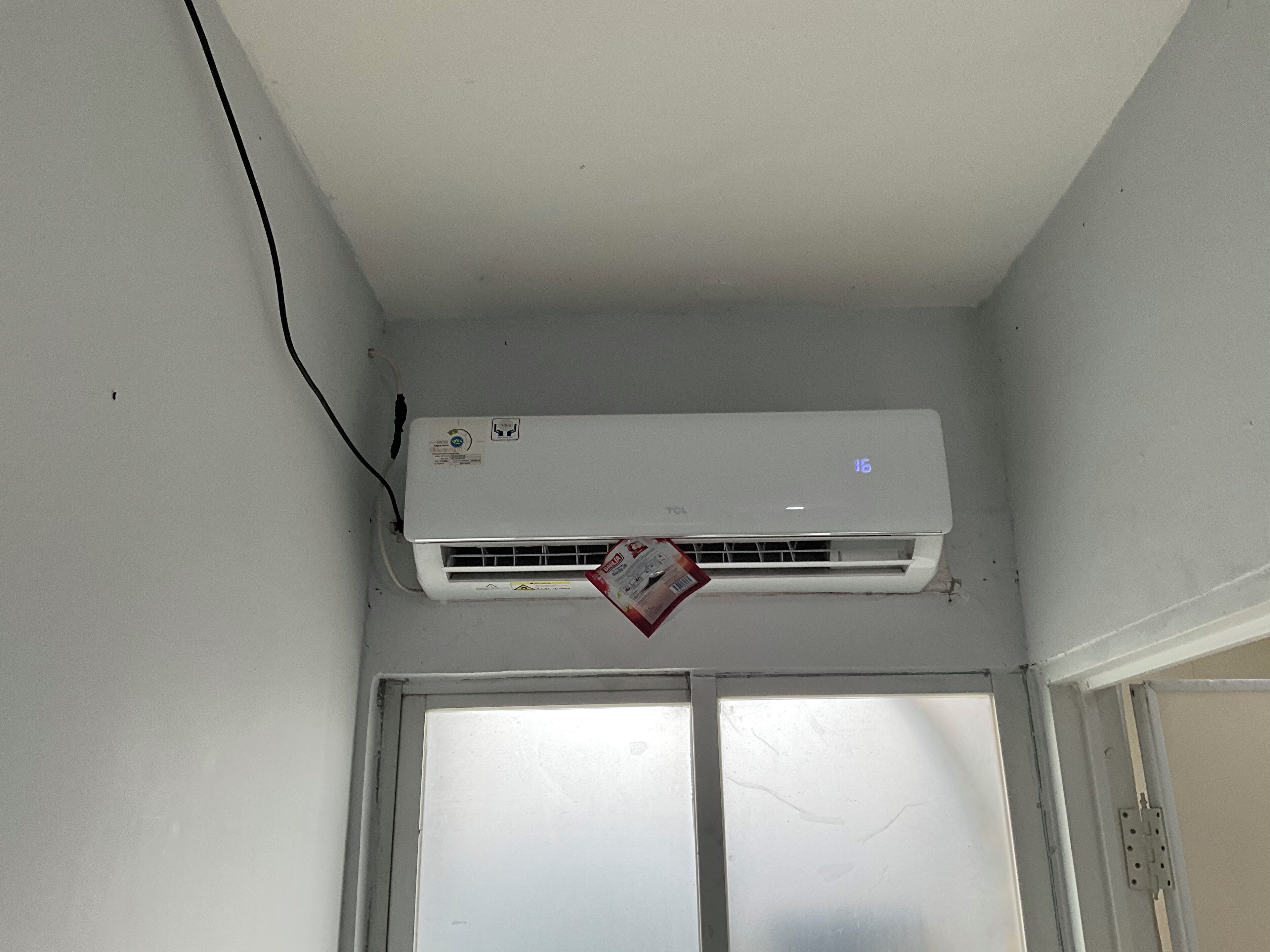 An air conditioning unit mounted on a wall with a window below it.