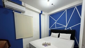 A modern bedroom with a bed, a chair, and a wall-mounted air conditioner. - Transit ID (Depok)
