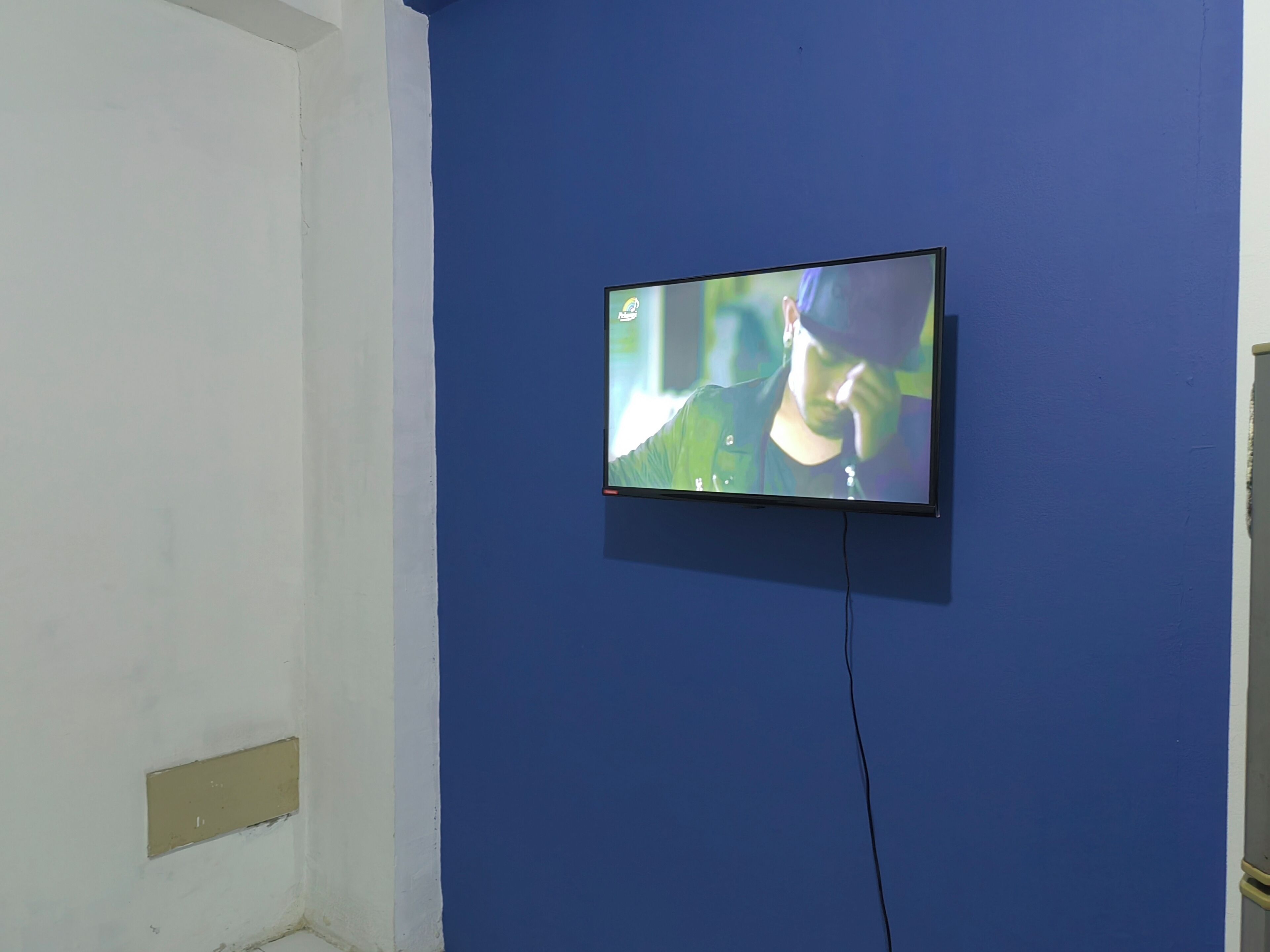A television mounted on a blue wall in a room with white walls.