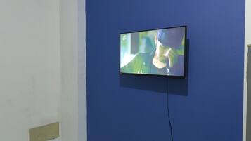 A television mounted on a blue wall in a room with white walls.