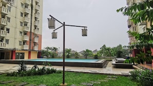 A residential area with a swimming pool, a street lamp, and a well-maintained lawn. - Transit ID (Depok)