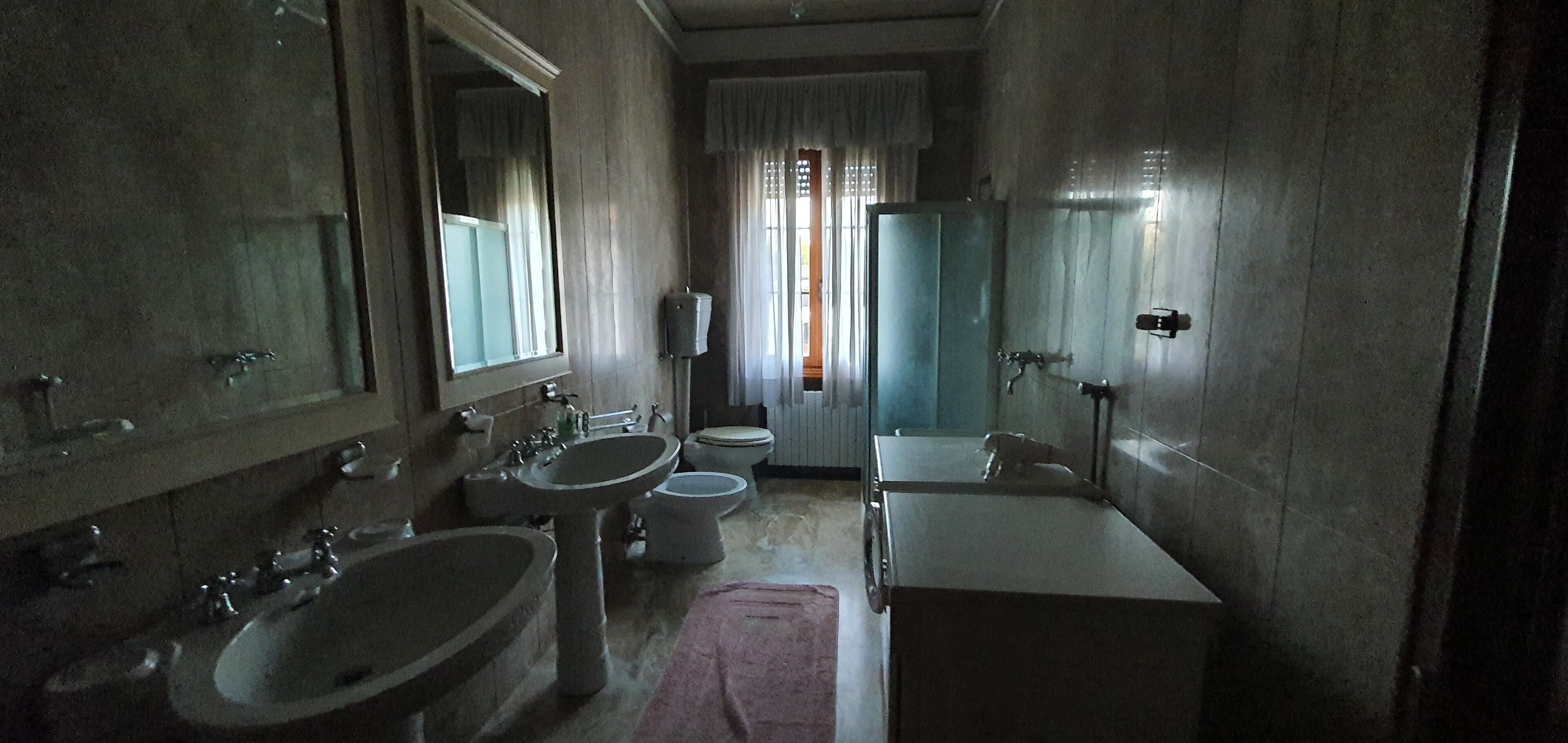 A bathroom with a large sink, a mirror, a toilet, and a bidet.