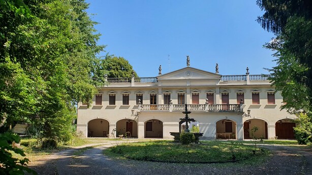 A classical building with a central courtyard, arched doorways, and a fountain.