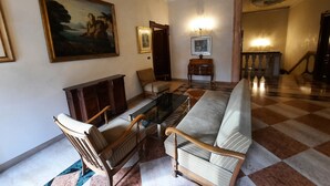 A spacious living room with a checkered floor, a sofa, a wooden coffee table, and a painting on the wall.