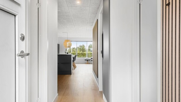 A modern hallway with a wooden floor, white walls, and a view of a dining area with a black table and chairs. - Awesome home in ørsted with WiFi (Ørsted)