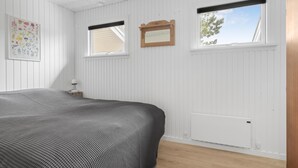A bedroom with a bed, two windows, a radiator, and a framed picture on the wall. - Awesome home in ørsted with WiFi (Ørsted)