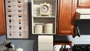 A kitchen with a coffee machine, a coffee type chart, a clock, and various kitchen utensils. - {Bunga-YOLO} Fun and Games in CLT's Best Neighborhood. Hot Tub NEW and working! (Charlotte)