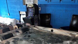 A hot tub with a marble-like exterior, blue walls, and a foosball table in the background. - {Bunga-YOLO} Fun and Games in CLT's Best Neighborhood. Hot Tub NEW and working! (Charlotte)