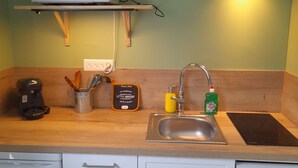 Una cocina compacta con microondas, pileta y un pequeño estante sobre la encimera.