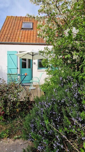 A quaint house with a tiled roof, a small balcony with a table and chairs, and a garden with purple flowers. - L'Argousier, Country House 4 Min. from Wissant Beach (Audembert)