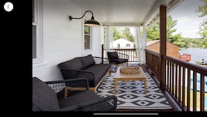 A covered porch with a sofa, chairs, and a table.