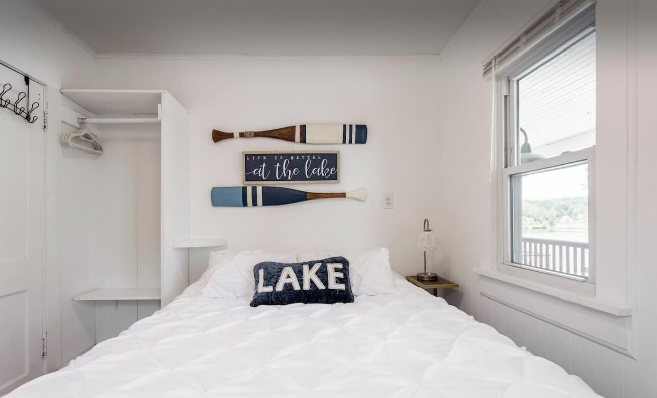 Un dormitorio con cama, ventana y adornos en la pared, incluyendo un letrero que dice 'en el lago'.