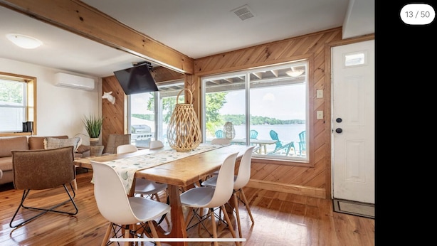 A dining area with a wooden table and chairs, a sofa, and a view of the outdoors.