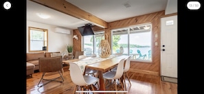 Un espace repas comprenant une table et des chaises en bois, un canapé et une vue sur l’extérieur.