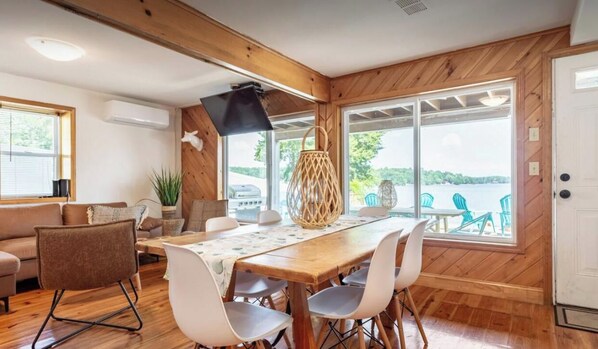 Un comedor con una mesa y sillas de madera, un sofá y vistas al exterior.