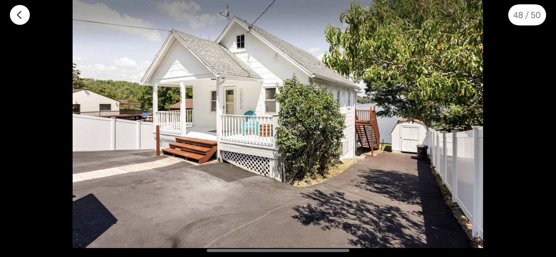 Une maison blanche d’un seul étage, dotée d’un porche, d’une petite terrasse et d’un jardin devant.