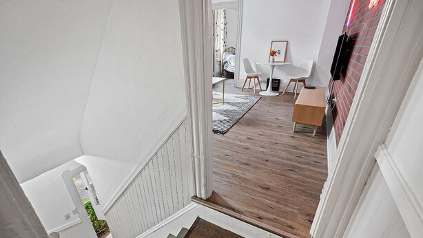 A staircase leading to a dining area with a white table, chairs, and a wooden bench. - Center of Little Italy #4 (Cleveland)