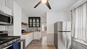 A modern kitchen with white cabinetry, a stainless steel refrigerator, a microwave, and a stove. - Center of Little Italy #4 (Cleveland)