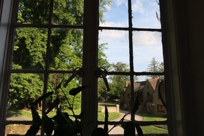 A window with a view of a green landscape and a building with a brick facade.
