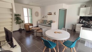 Una sala moderna con un sofá, una mesa de comedor con sillas y una zona de cocina con armarios y electrodomésticos.