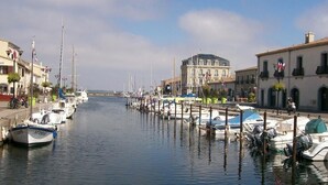 Un puerto deportivo con barcos amarrados a lo largo de la costa, edificios con balcones y un cielo despejado.