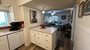 A kitchen with white cabinets, a coffee maker, and a wooden floor. - Boutique Beachside condo with easy access to beach (St. Augustine)