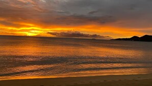 Une plage avec un coucher de soleil sur l’eau.