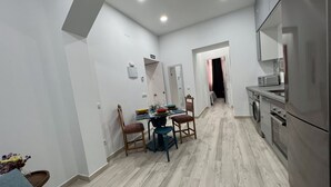 Ett modernt kök med kylskåp, mikrovågsugn och ugn. Det finns en matplats med ett bord och stolar, och en tvättmaskin står i hörnet.
