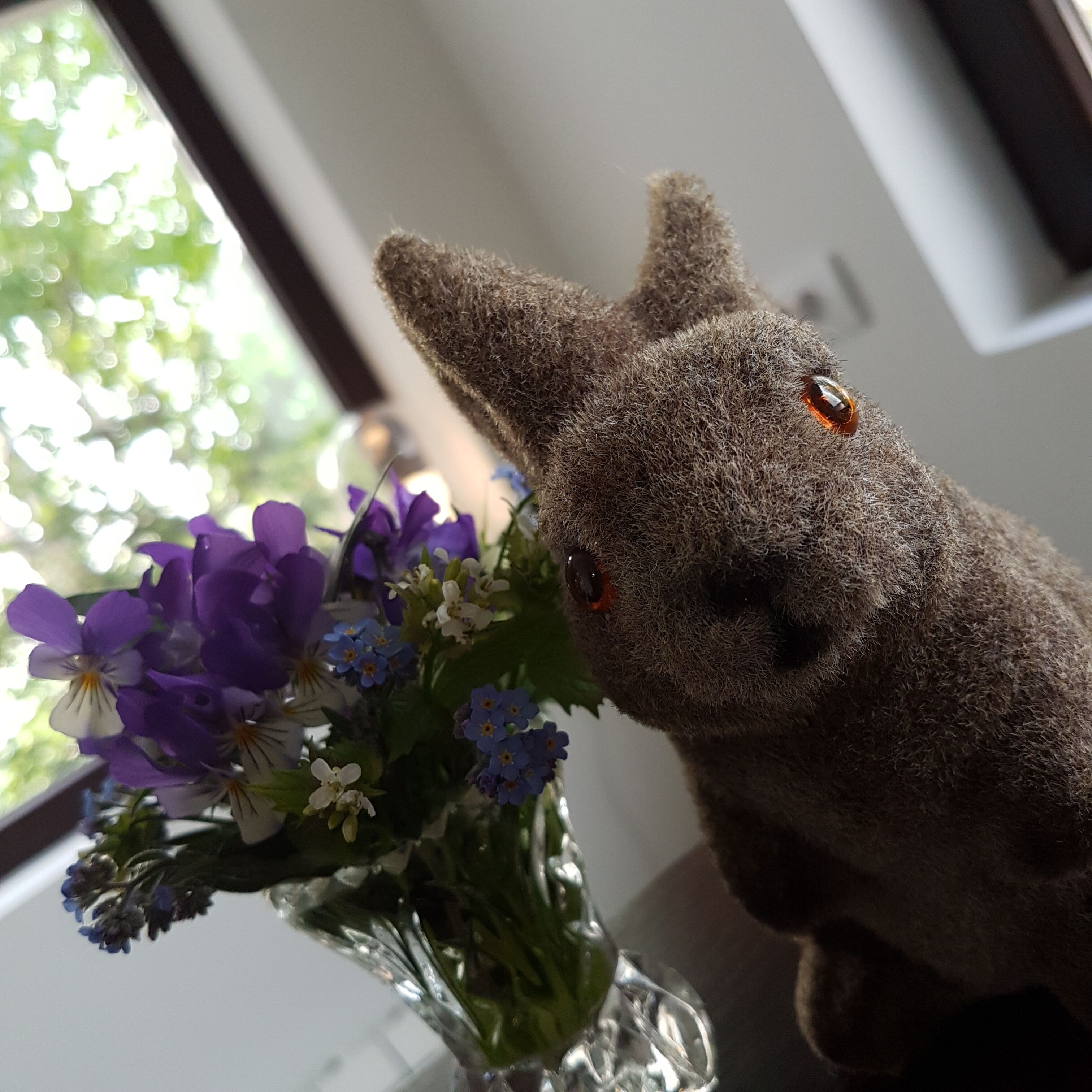 Un lapin en peluche est posé à côté d’un vase rempli de fleurs.