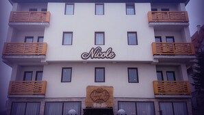 Un hotel de varios pisos con un llamativo letrero que dice "Nicole" en la fachada.