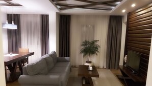 Una sala de estar moderna con un sofá, una mesa de centro, un televisor y una mesa de comedor.