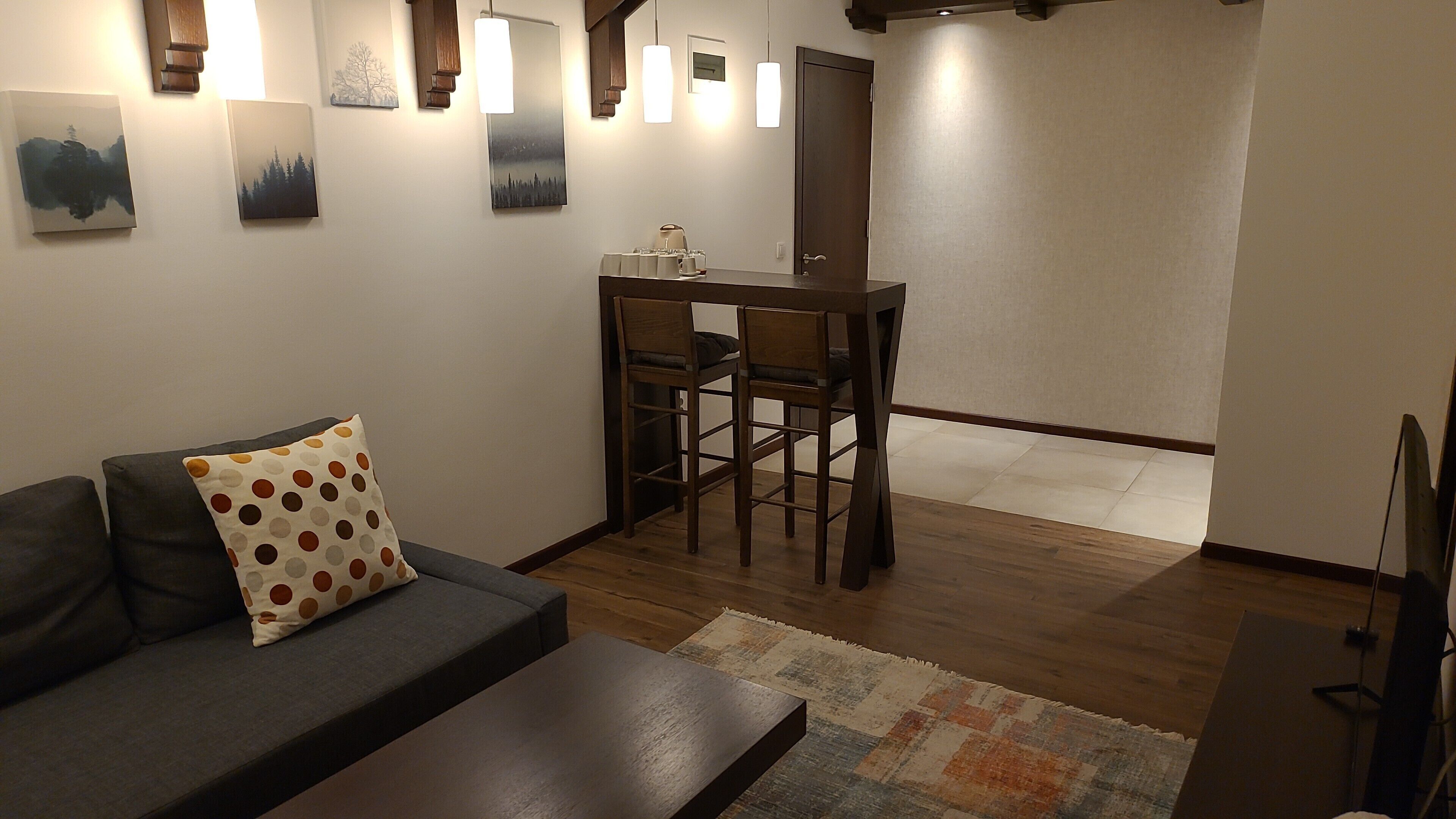 Ein Wohnzimmer mit Sofa, Couchtisch, Esstisch mit Stühlen und Bildern an den Wänden.