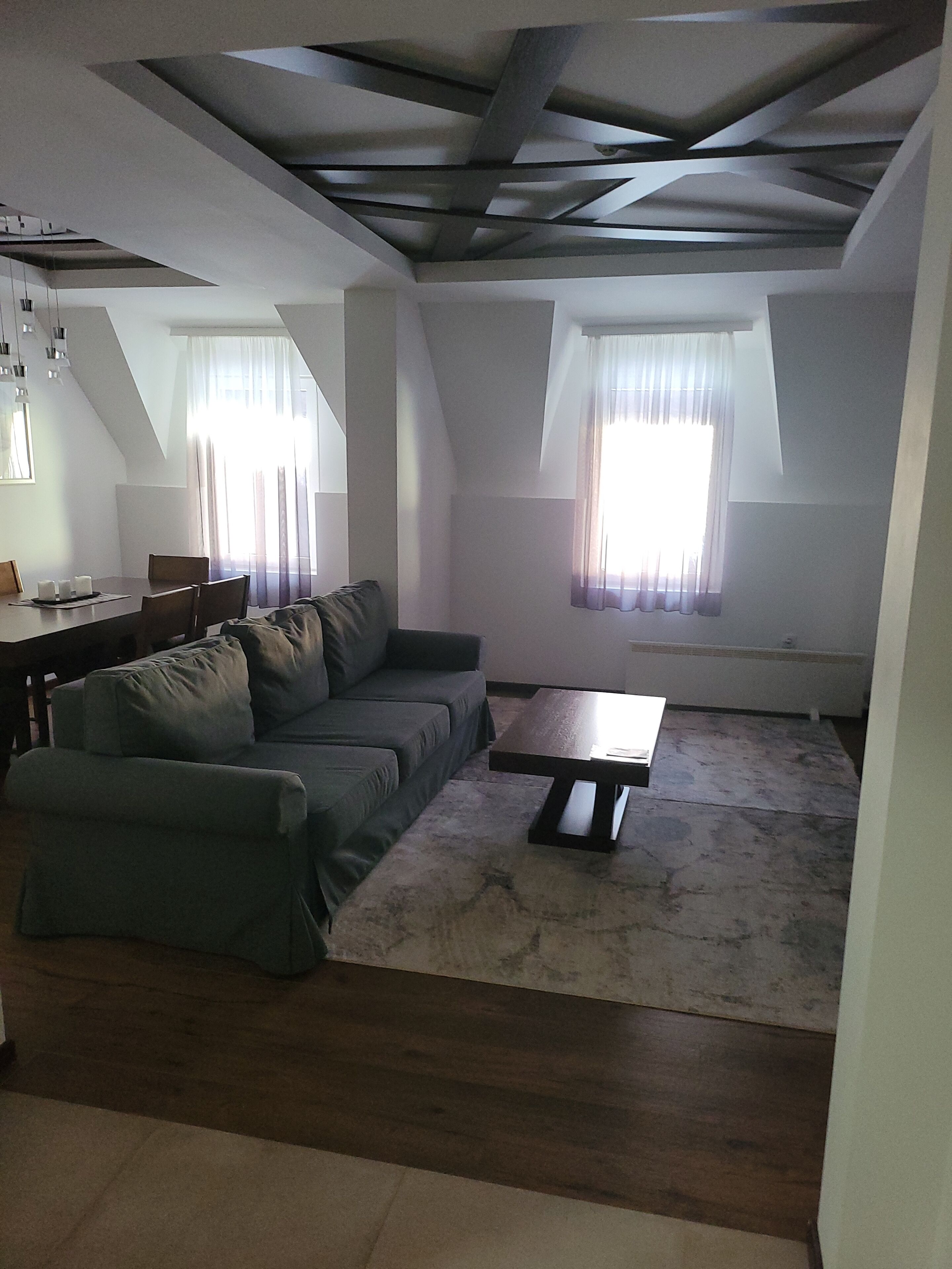Ein modernes Wohnzimmer mit einer Eckcouch, einem Couchtisch und einem Essbereich mit Tisch und Stühlen.