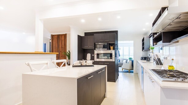 Una cucina moderna con isola centrale, elettrodomestici integrati e vista sull'area living.