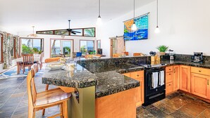 A spacious kitchen with granite countertops, wooden cabinets, and a black stove.