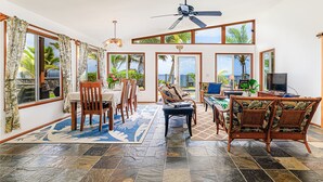 A spacious living area with a dining table, chairs, a sofa, and a television.