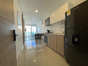 A modern kitchen with a black refrigerator, wooden cabinets, and a stainless steel sink.