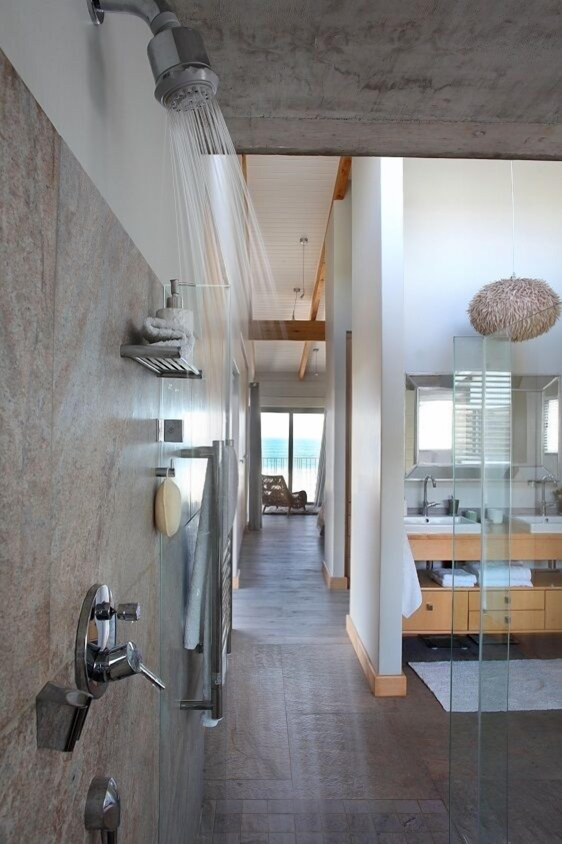 Un bagno moderno con doccia, un vanità con vetri e vista sull'esterno.