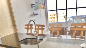Una cocina con un lavamanos de acero inoxidable, armarios de madera y una ventana con vistas a una zona de estar al aire libre.