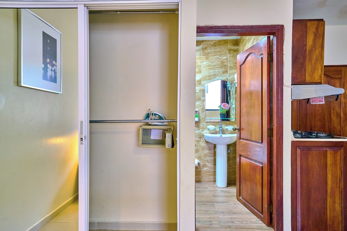 Une pièce avec une porte en bois, un lavabo blanc et une petite fenêtre.