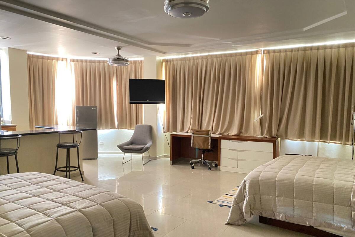 Une chambre d’hôtel avec deux lits, un bureau, une chaise, une télévision et un mini-bar.