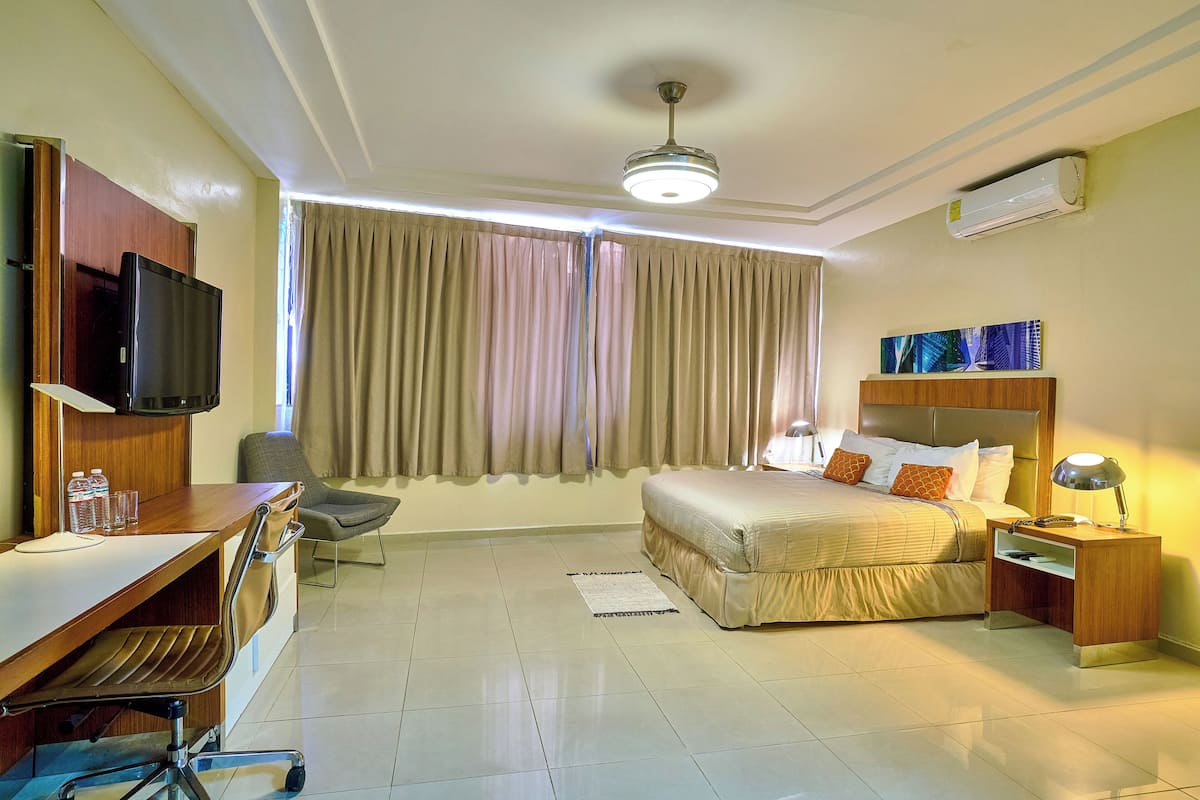 Une chambre d’hôtel comprenant un lit, un bureau avec une chaise, une télévision et une table de chevet avec une lampe.