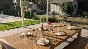 A wooden dining table set for four with wine glasses, plates, and cutlery. - [Egg Farm Ranch] Heated Pool - Water Slide - Hot Tub - Dog Friendly (Kenwood)