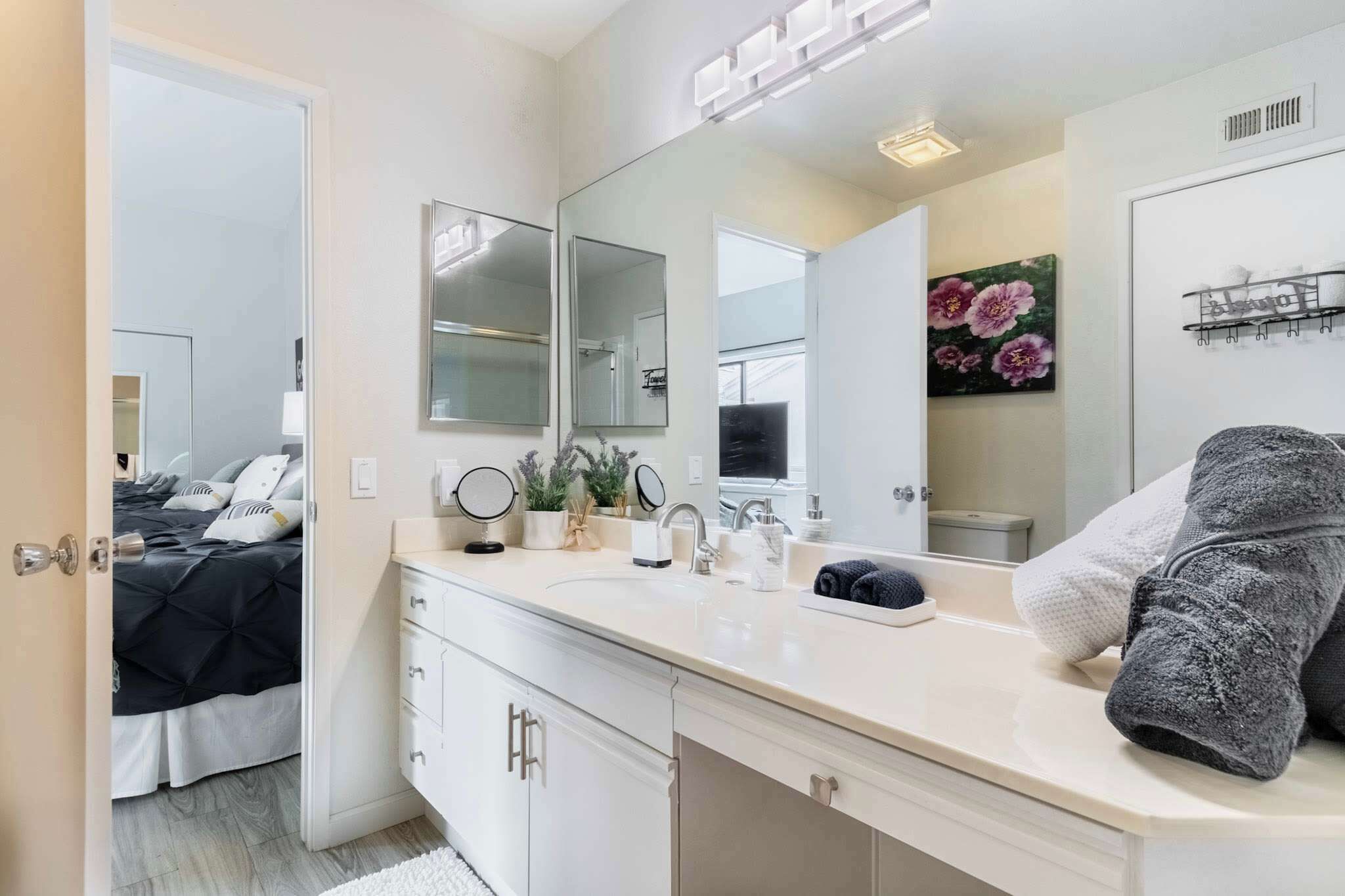 A modern bathroom with a large mirror, a sink, and a shower area.
