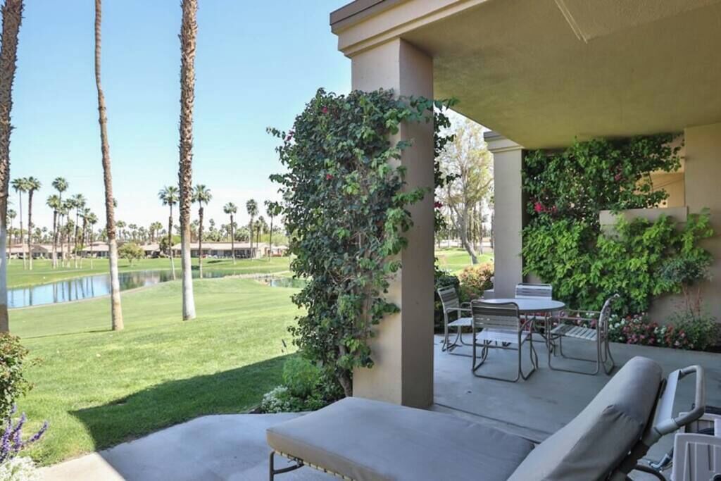A patio with a table and chairs, a covered seating area, and a view of a golf course.