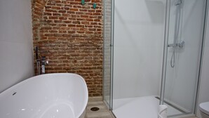A bathroom with a freestanding bathtub, a glass-enclosed shower, and a white toilet.