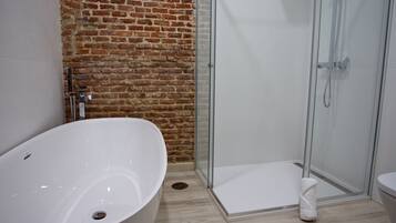 A bathroom with a freestanding bathtub, a glass-enclosed shower, and a white toilet.
